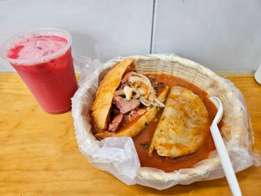 Torta Ahogada: Meksika usulü boğulmuş domuz sandviçi, baharatlı kırmızı sos. Kızarmış masa eşyasıyla servis edilir, ahşap üzerinde ferahlatıcı kırmızı içecek. Samimi, otantik.