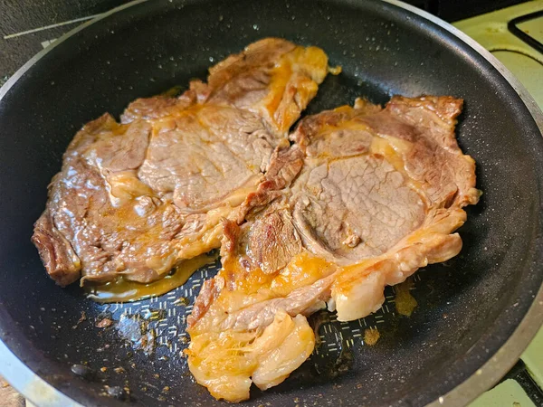 İki sulu biftek soba tepsisinde pişiyor ve kahverengileşiyor. Lezzetli bir yemek hazırlıyorlar.