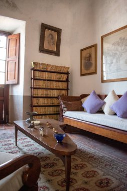 Cocula, Meksika - 27 Nisan 2025: Eski Meksika çiftliğinde kitaplar, klasik mobilyalar ve pencere ışığı bulunan zarif tarihi oda