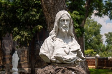 Guadalajara, Meksika - 6 Eylül 2025: Mezquitan Pantheon, Guadalajara, Meksika 'da İsa Mesih' in beyaz taş büstü. Yeşil ağaçlarla güneşli bir gün ruhani bir hava yaratır.