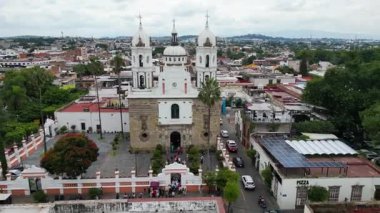 Capilla del Santisimo 'nun havadan görünüşü, Tlaquepaque, Meksika' da bir koloni kilisesi. Geleneksel binalar, yeşil ağaçlar, bulutlu gün.