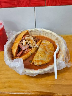 Geleneksel Meksika Torta Ahogada 'sı ve lezzetli bir quesadilla baharatlı kırmızı acı biber sosuna batırılmış kırsal bir sepette.