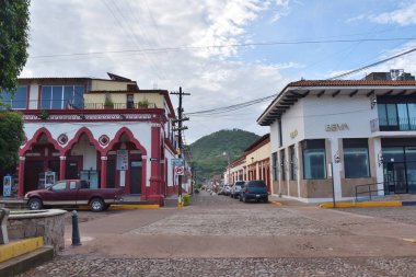 Mascota, Meksika - 17 Temmuz 2024: Arka planda kaldırım taşı yolu ve manzaralı tepe ile geleneksel ve modern mimarinin bir karışımının yer aldığı Mascota, Jalisco 'daki ana caddenin görüntüsü