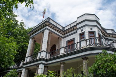 Guadalajara, Meksika 23 Ağustos 2025, Juarez Bulvarı 'ndaki klasik beyaz Casona binası. Zarif mimari, balkonlar, taş sütunlar ve gür ağaçlar.