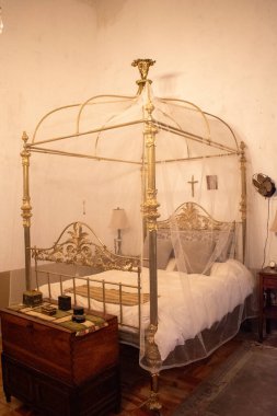 Geleneksel bir hacienda yatak odasında ahşap göğüslü narin ağlarla süslü şık bir yatak.