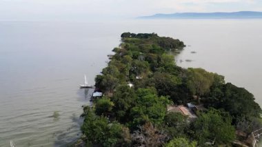 Hava aracı Meksika Chapala Gölü 'ndeki Akrepler Adası' nı yoğun yeşil bitki örtüsü, sakin göl suları ve bulutlu bir günde uzak dağlarla görüntüledi.