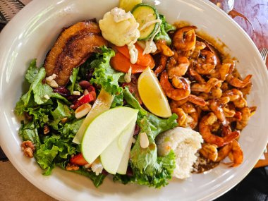 Lezzetli bir yemeğin tepeden tırnağa görüntüsü. Lezzetli karides, taze salata, beyaz pirinç ve kızarmış muz. Sağlıklı ve iştah açıcı bir yemek.