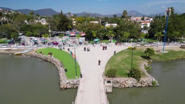 Chapala 'nın Malecon' u ve Meksika 'daki Chapala Gölü' ndeki dairesel rıhtım, insanların gezdiği, şehir binalarının ve dağların altında güneşli bir gökyüzünün altında.