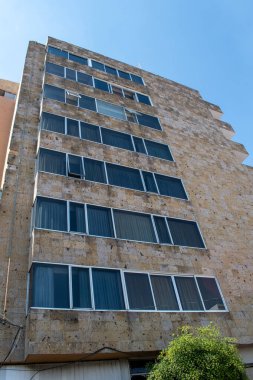 Guadalajara, Meksika - 8 Kasım 2025: Guadalajara, Meksika 'da modern bir bina, birçok pencere ve güneşli bir günde alçak bir açıdan görülen açık mavi bir gökyüzü yer alıyor.