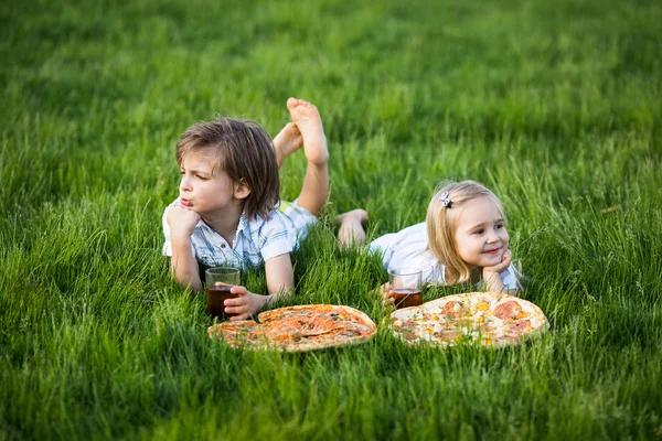 Bror och syster på sommar picknick med pizza — Stockfoto