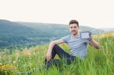 adam üstünde belgili tanımlık tepe oturur ve bir ebook bir elinde tut