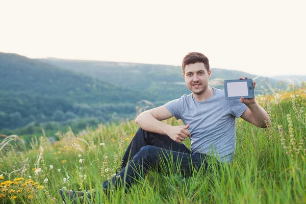 Man op de heuvel houden een ebook met een wit scherm — Stockfoto