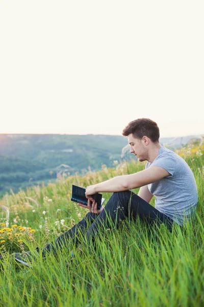 Uomo seduto sulla collina e leggere un libro verticale — Foto Stock