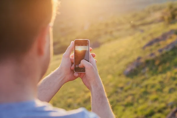 adam günbatımı bir fotoğraf çeker