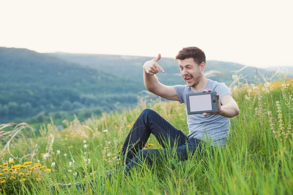 Smiling man winks and hold an eBook — Stock Photo, Image