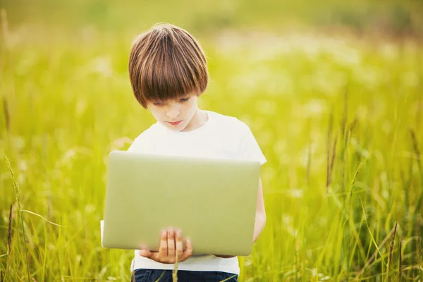 Niño pequeño con portátil en la naturaleza — Foto de Stock