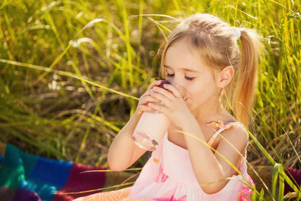 Lilla flickan dricka yoghurt på picknick — Stockfoto