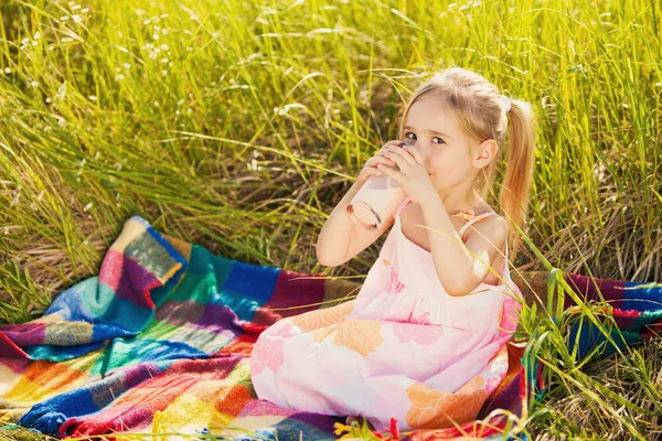 Lilla flickan dricka yoghurt på Pläd — Stockfoto