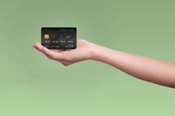 Black credit card isolated on green background — Stock Photo, Image