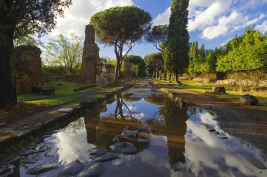Fırtınadan sonra Appian Yolu 'nda güzel bir an, göletin maviliği ve bir sonbahar gününde bulutlarla birlikte göletteki ağaç mezarlarının kalıntılarını yansıtır. Regina Viarum, Roma İtalya.
