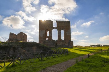 Villa dei Quintili, Roma, termal banyolar, günbatımında kalidaryumun tuğla yapısının gösterişli bir görüntüsü güneş batımından, harabelerden, mavi gökyüzünden ve Via Appia 'nın bulutlarından yükseliyor..