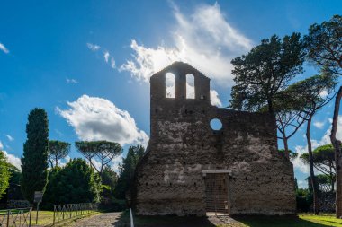 Roma, Via Appia Antica ve Capo di Bove 'daki San Nicola Kilisesi, gökyüzü mavisi, bulutlar, deniz çam ağaçları ve selvi tarafından çerçevelenen cephenin ayrıntıları. Roma Capo di Bove.