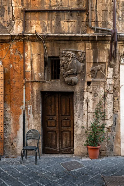 ユダヤ人地区 ゲットーで オレンジの建物の木製のドアの詳細 古代ローマの碑文の挿入と ライオンの浅浮き彫り 椅子と植物 ルンゴーフェール ローマ — ストック写真