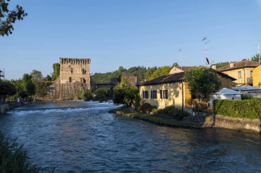 Güzel ortaçağ köyü Borghetto di Valeggio sul Mincio. Köprü ve çiçek açan bahçeli ortaçağ kulesi nehrinin ayrıntıları. Verona ili, Veneto, İtalya