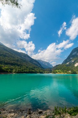 Cavedine Gölü. Turkuaz suların manzarası, bitki örtüsü bakımından zengin alp dağları. Mavi gökyüzü ve bulutlar bir yaz gününde. Trentino, Trento