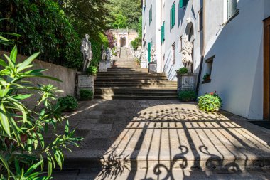 Monselice 'in ortaçağ köyünde mermer heykellerle dolu bir merdivendeki demir kapının gölgesi kaleye doğru yürüyor. Padua, Veneto, İtalya.