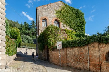 Monselice 'in ortaçağ köyü, mavi gökyüzü, bulutlar ve taş yolun tuğla binalarının olduğu bir günde kaleye doğru yürü. Padua, Venedik. İtalya..