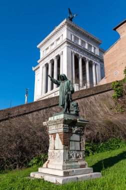 Campidoglio 'nun merdivenlerinden, Roma' nın merkezine uzanan anavatanın sunağına bakan Cola di Rienzo 'nun mermer heykelinin ayrıntıları. Mavi gökyüzünün olduğu bir günde yeşil çimenler.