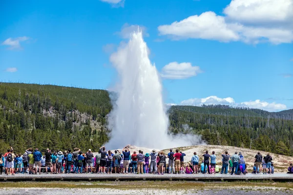 Turistas observando la erupción de los Viejos Fieles en Yellowstone Natio —  Fotos de Stock