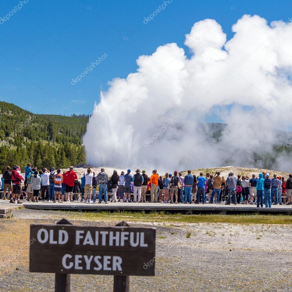 Tourists watching the Old Faithful erupting in Yellowstone Natio