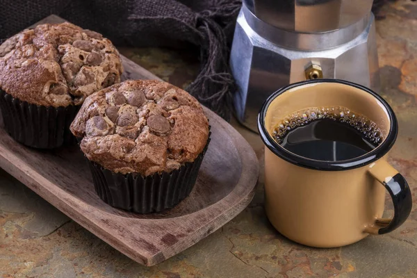 delicious chocolate muffins, a coffee mug and a traditional Italian coffee maker.