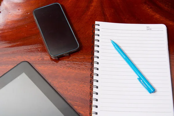 Ahşap masa üstünde defter ile tablet ve kalem