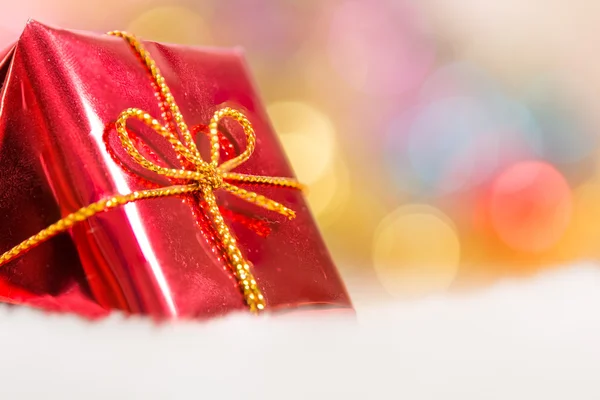 Christmas background with bokeh and red gift box in snow Royalty Free Stock Photos