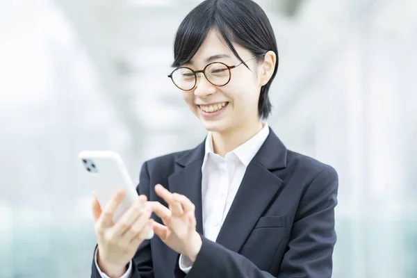 Takım Elbiseli Gözlüklü Asyalı Genç Bir Kadın Akıllı Telefon Kullanıyor — Stok fotoğraf