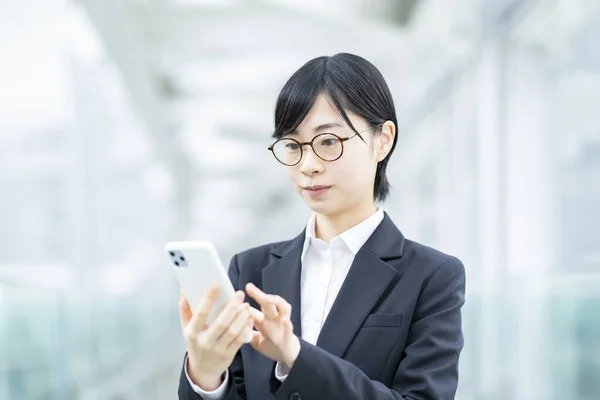 Takım Elbiseli Gözlüklü Asyalı Genç Bir Kadın Akıllı Telefon Kullanıyor — Stok fotoğraf