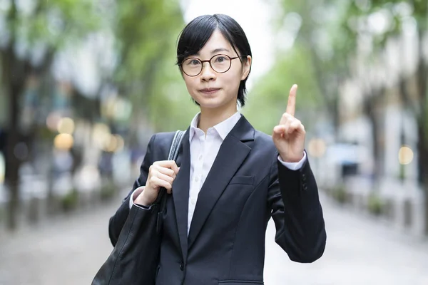 Een Jonge Vrouw Een Pak Poseert Met Haar Wijsvinger Omhoog — Stockfoto