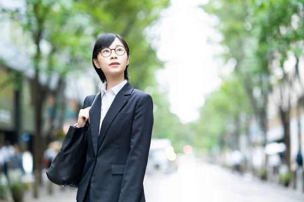 街路樹の並ぶ通りに立つスーツ姿の若い女性 — ストック写真