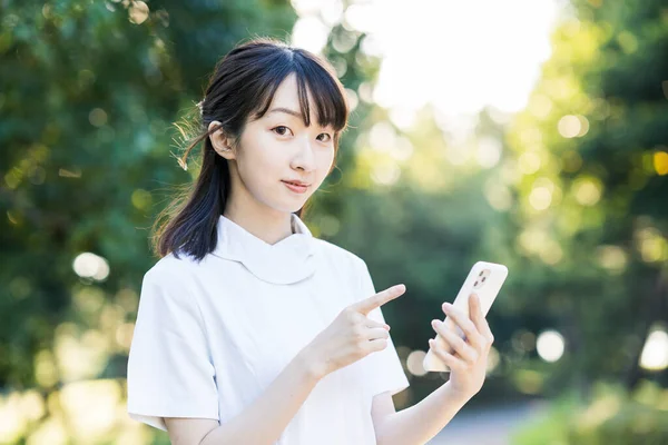 アジアの若い女性の白い服にスマートフォン — ストック写真