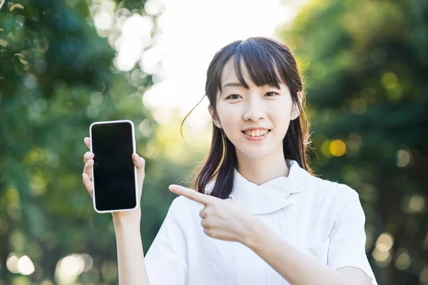 Beyaz Elbiseli Akıllı Telefonlu Asyalı Genç Bir Kadın — Stok fotoğraf