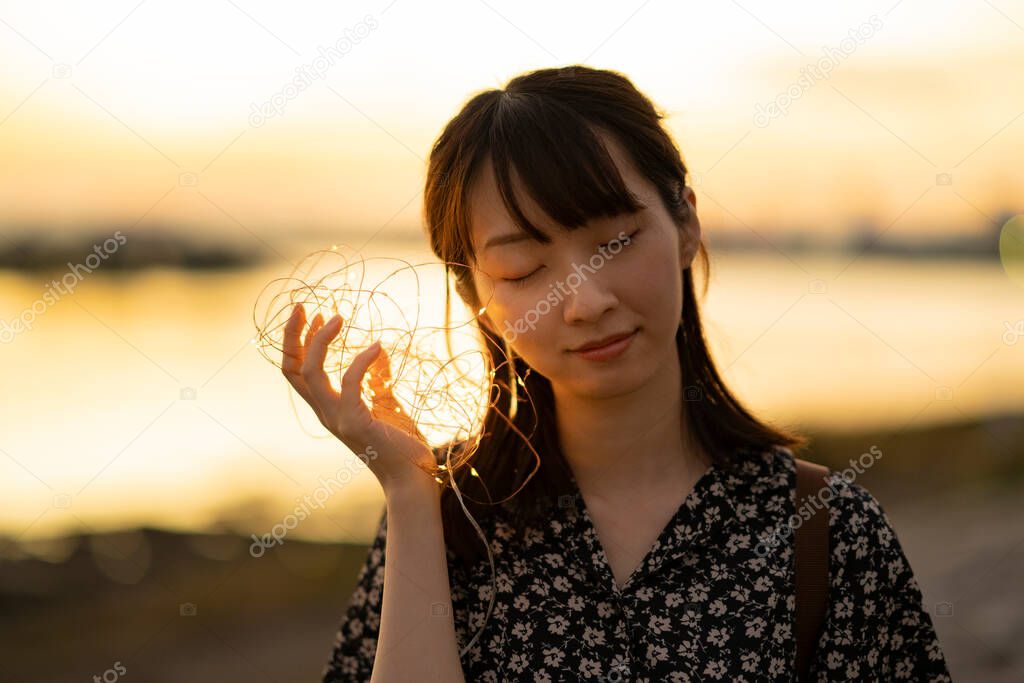 A young woman who brings the illumination lights closer to her ear