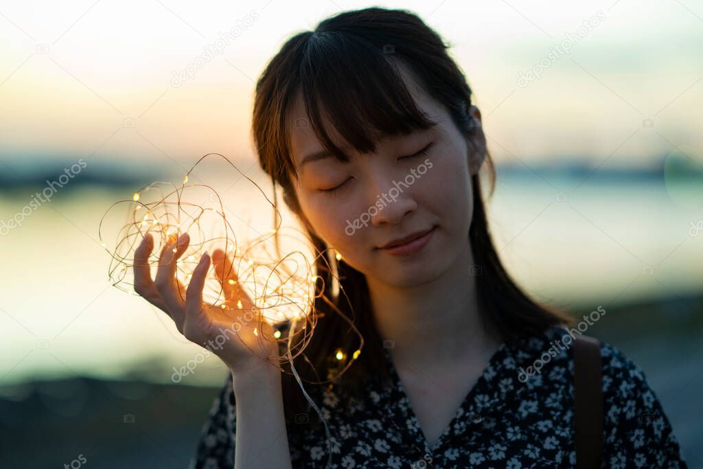 A young woman who brings the illumination lights closer to her ear