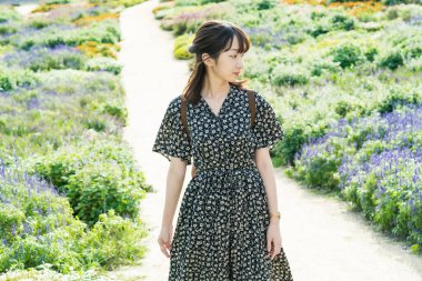 Asyalı genç bir kadın çiçek tarlasında yürüyüş yapıyor.