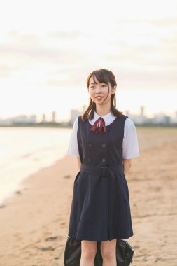 Sahilde yürüyen Asyalı lise öğrencisi.