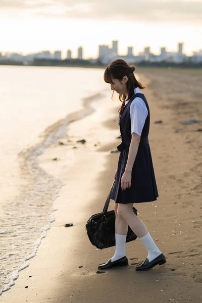Asian female high school student walking on the beach