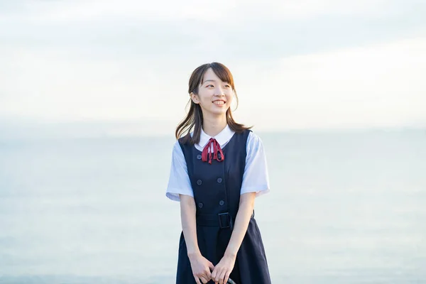 笑顔と海の背景を示す女子高生 — ストック写真