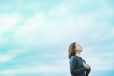Sıradan giyinmiş Asyalı iş kadını gökyüzüne bakıyor.